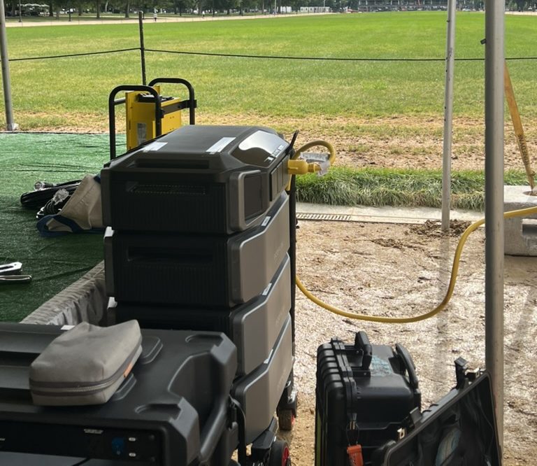 EcoFlow generator stack + Champion Pro PDU set up under an event tent on a grass lawn
