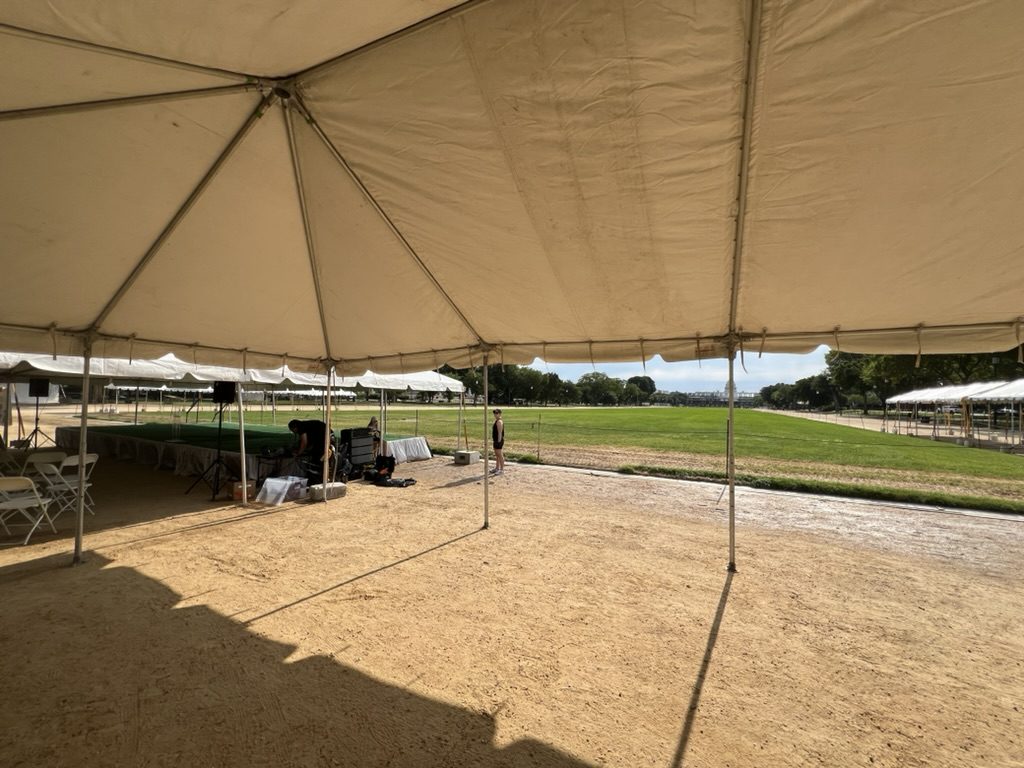 Interior of a large event tent — speakers, stage, and mixing rig