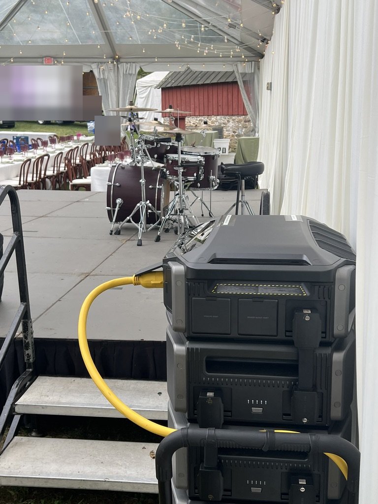 Battery stack feeding a band stage inside a tented wedding reception